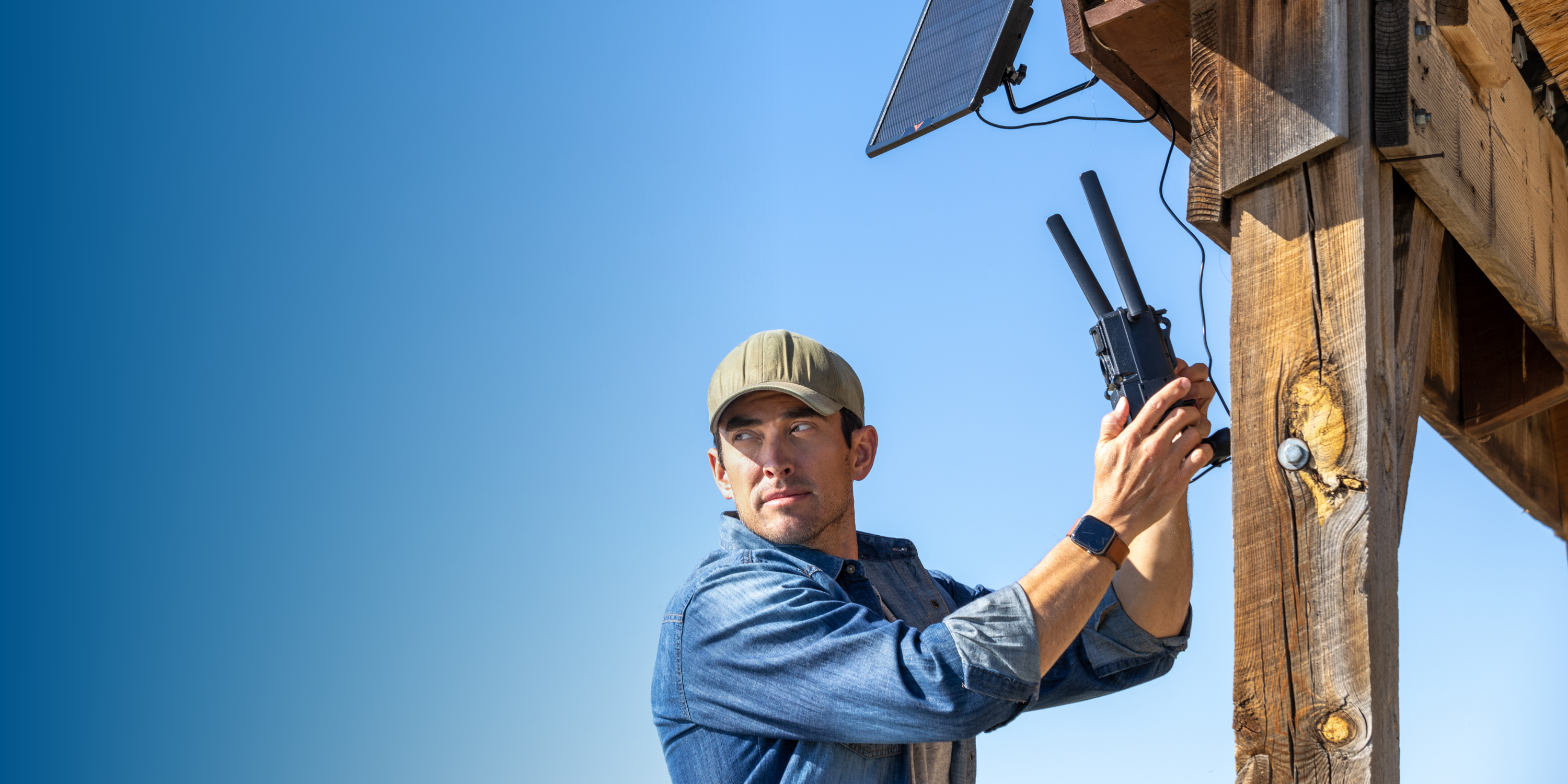 Man installing a solar panel and device on a wooden structure.
