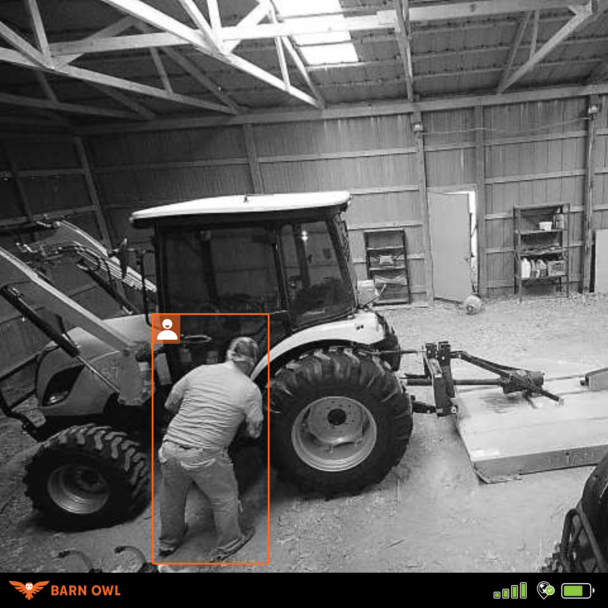 Person standing near a tractor inside a barn.