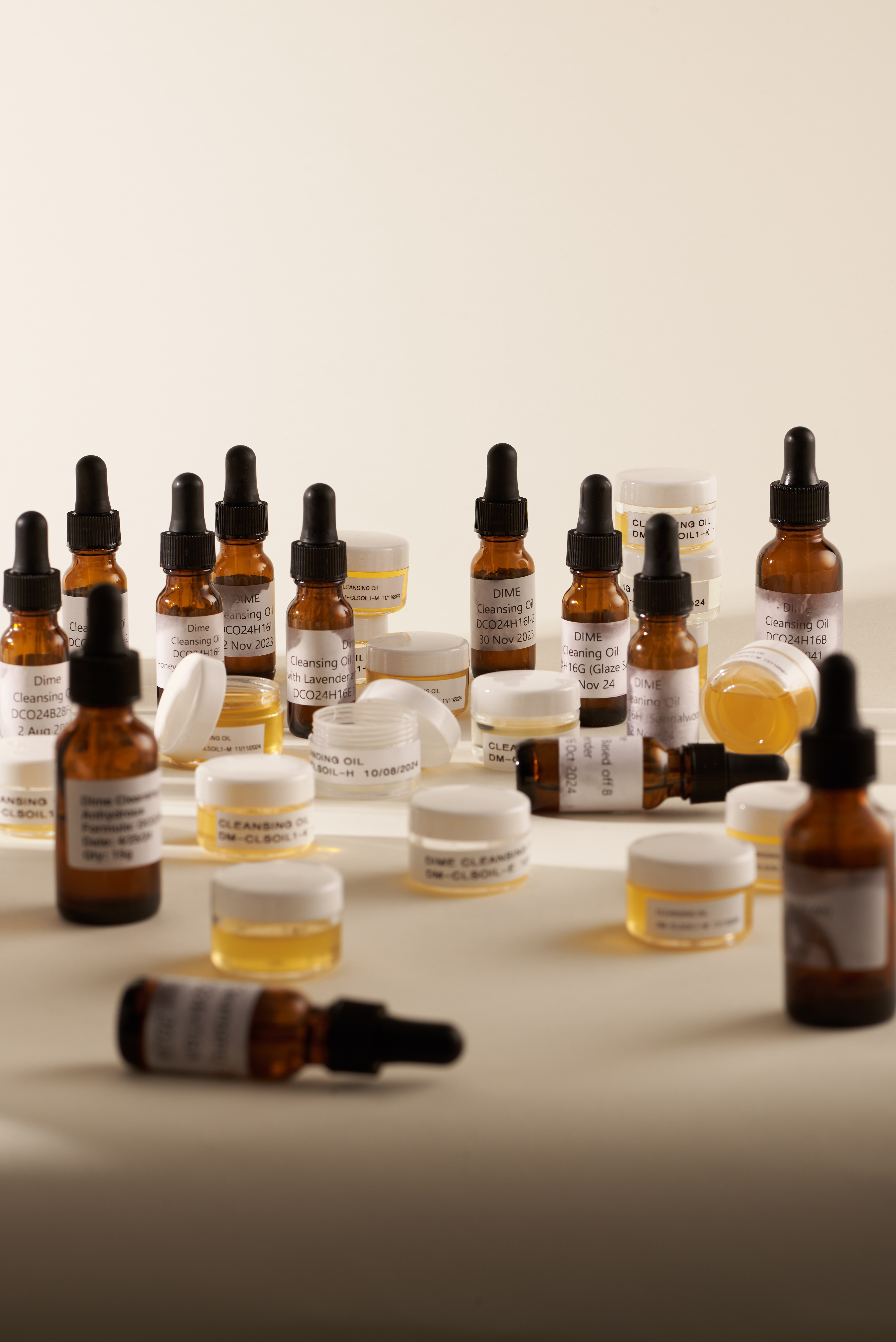 Assorted small bottles and jars with droppers on a neutral background.