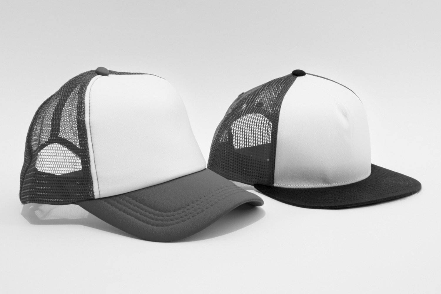 Two black and white trucker hats on a plain background.