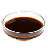 A small clear glass bowl filled with a dark brown liquid against a white background.