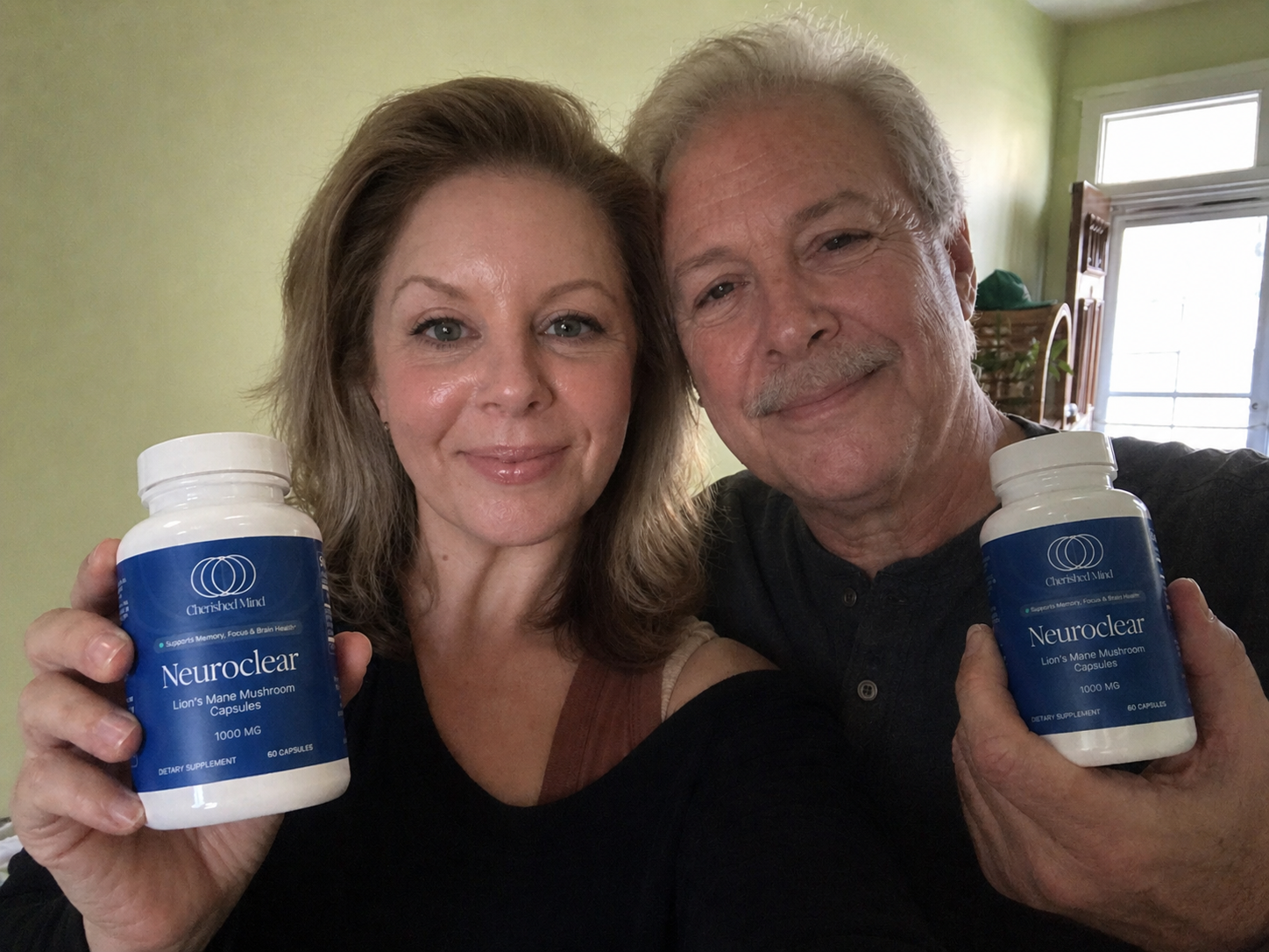 A smiling man and woman each hold a white bottle of Neuroclear Lion's Mane Mushroom Capsules.