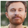 A person with a beard and mustache, wearing a yellow shirt, outdoors.