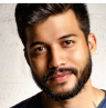A person with a beard and short hair smiling at the camera.