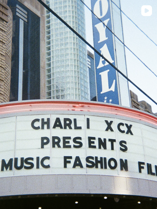 A low-angle shot of a theater marquee advertising 'CHARLI XCX PRESENTS MUSIC FASHION FILM'.