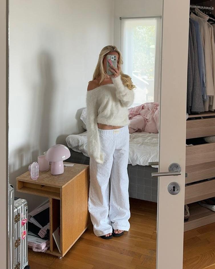 Person taking a mirror selfie in a cozy bedroom with soft lighting.