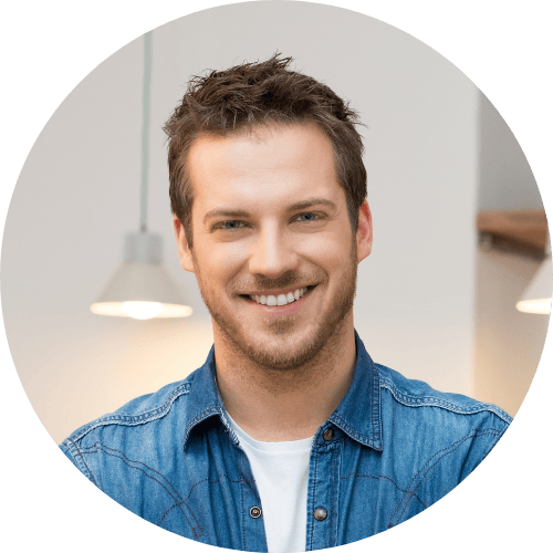A circular headshot of a smiling man with light brown hair wearing a denim shirt over a white shirt.