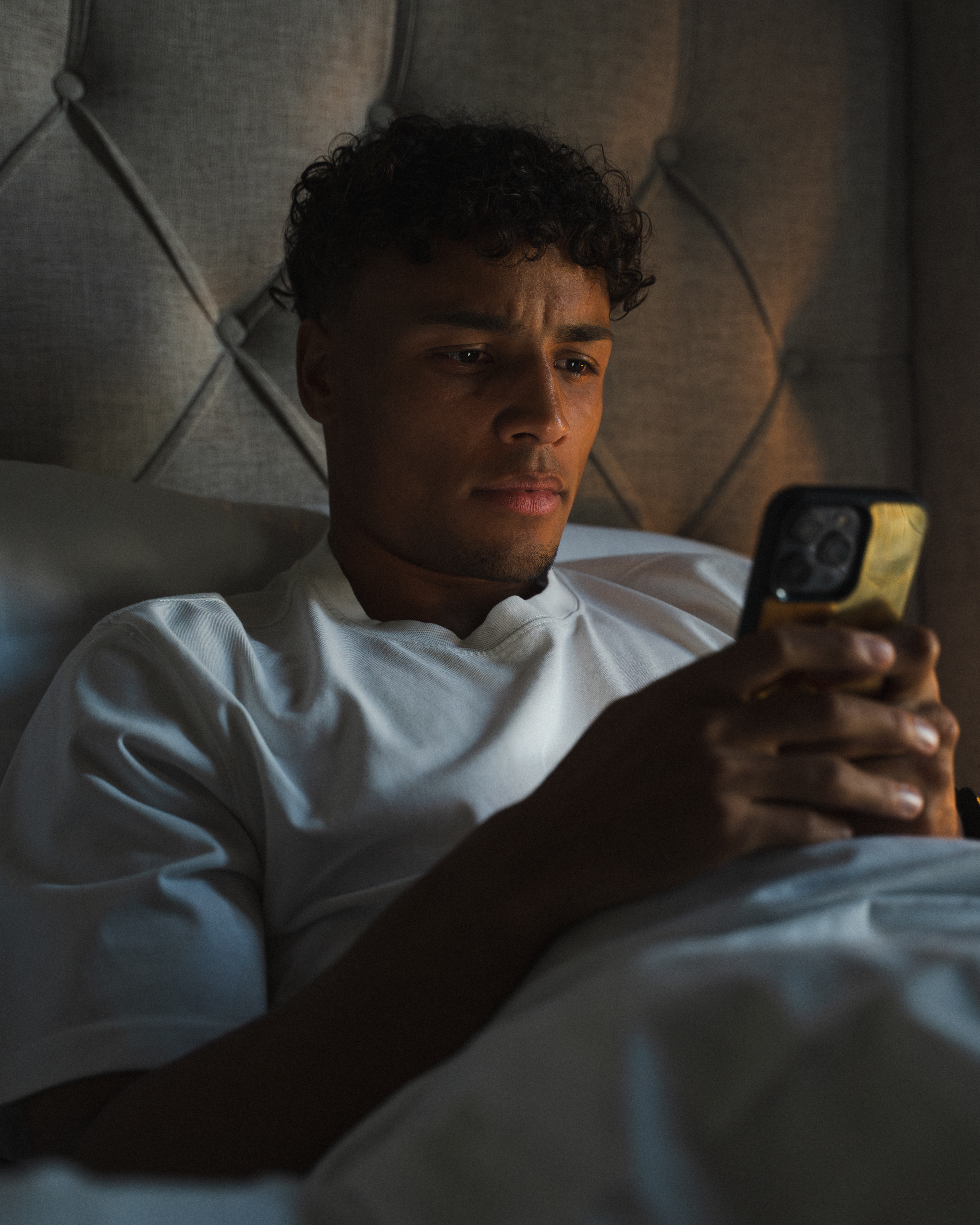 Person lying in bed, looking at a smartphone.