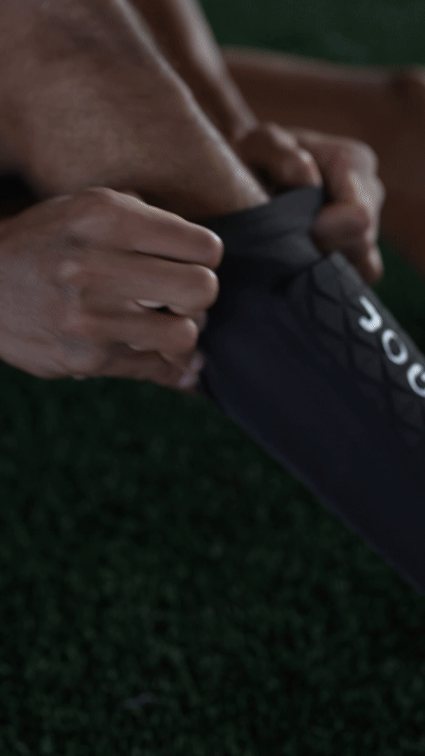 Person adjusting a black shin guard on their leg.
