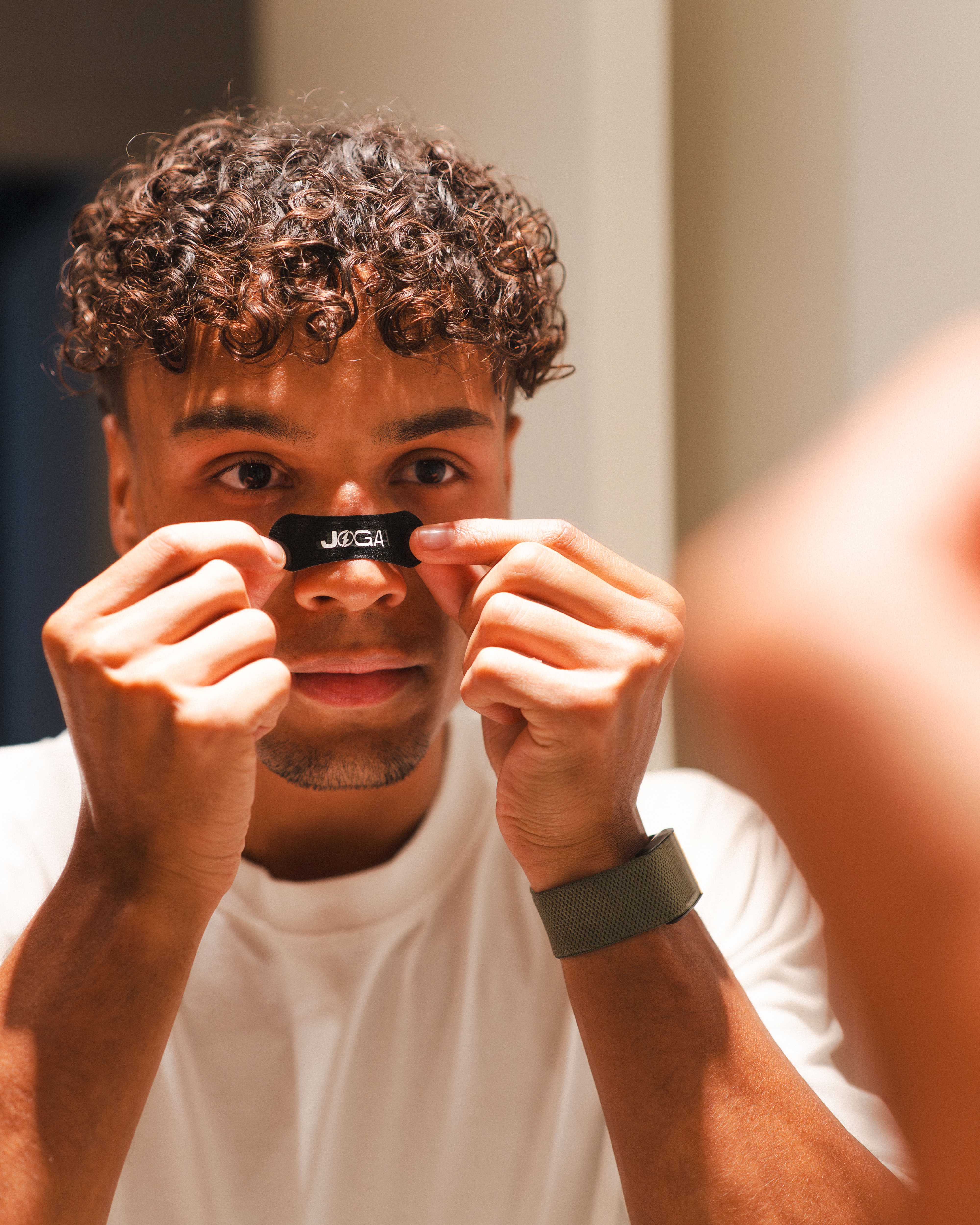 Person applying a black nose strip in front of a mirror.