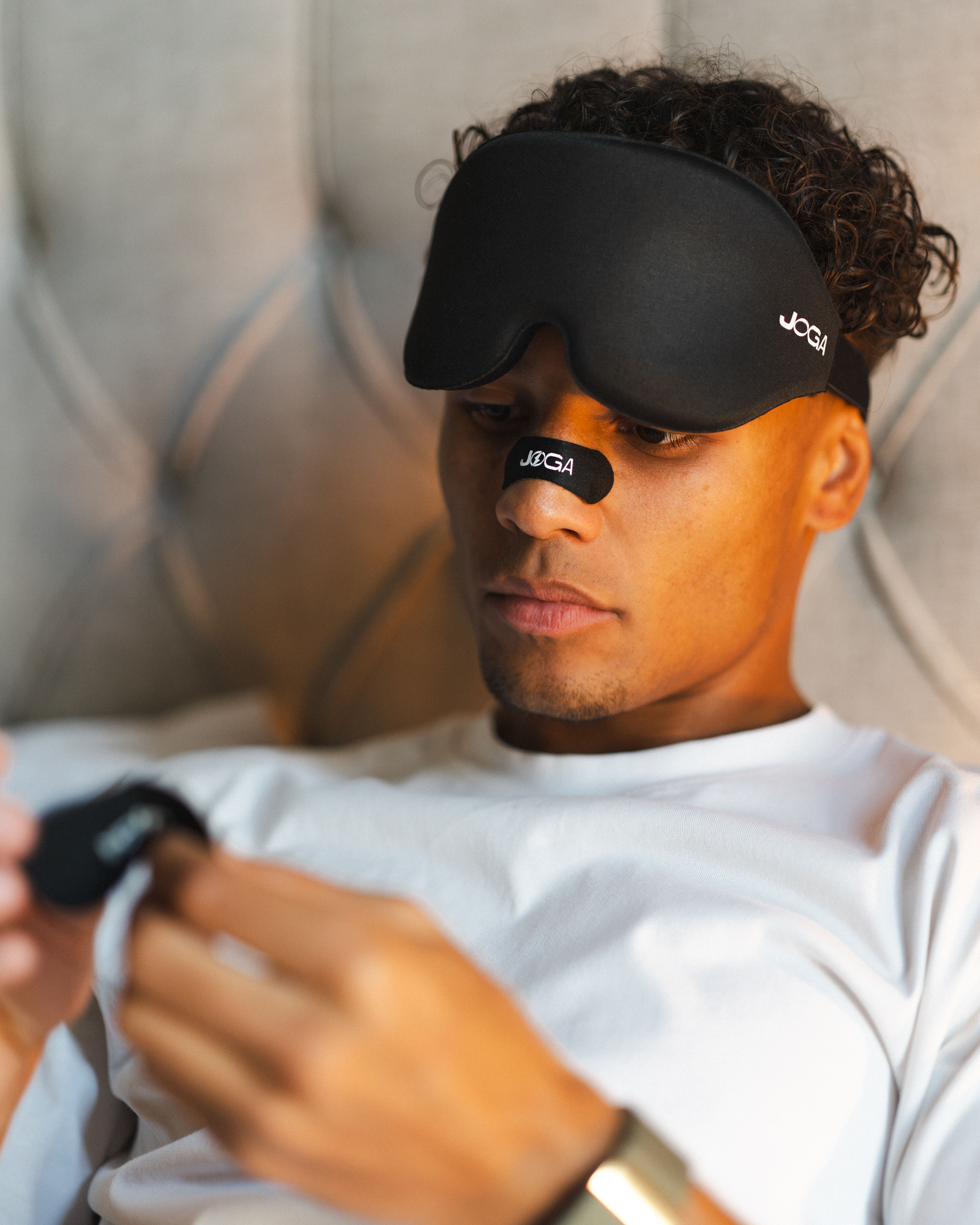 Person wearing a black eye mask and nose strip, holding an object.