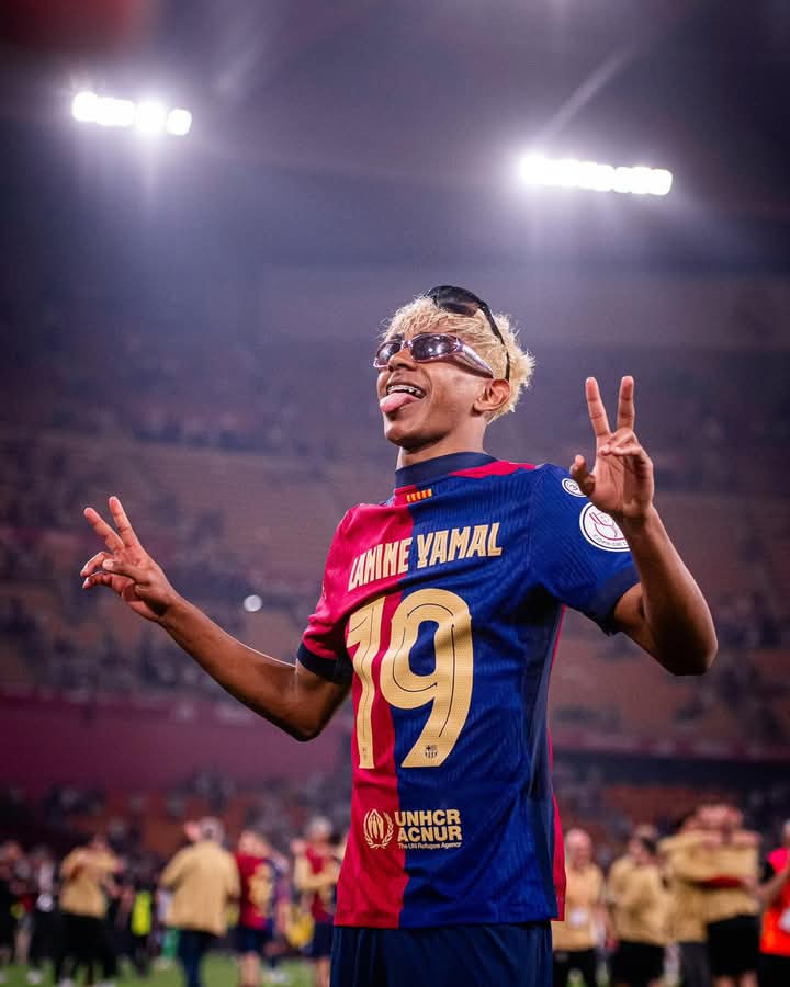 Soccer player in a blue and red jersey celebrating on the field.