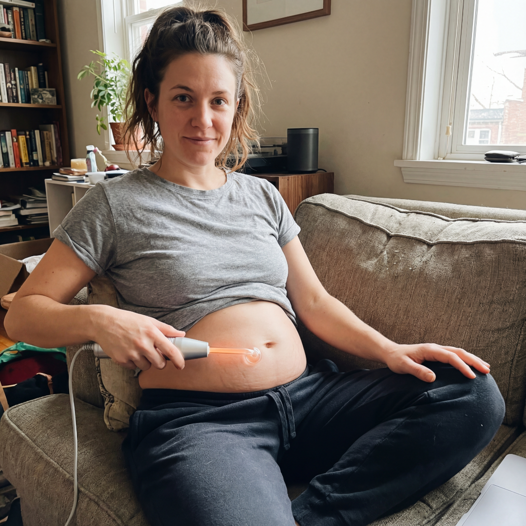 Person sitting on a couch using a handheld device on their stomach.