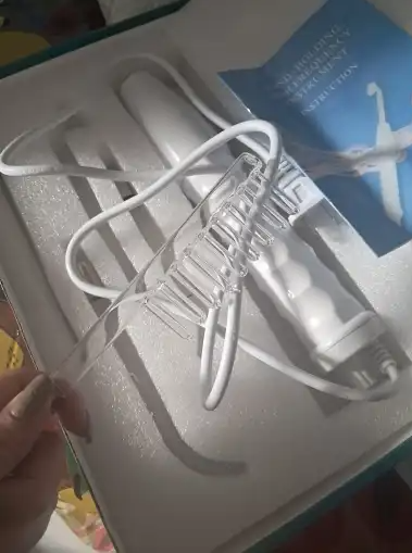 White hair styling tool with cord and attachments in a box.
