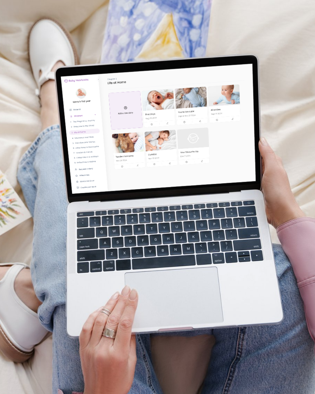 Person using a laptop with a baby photo album interface displayed.