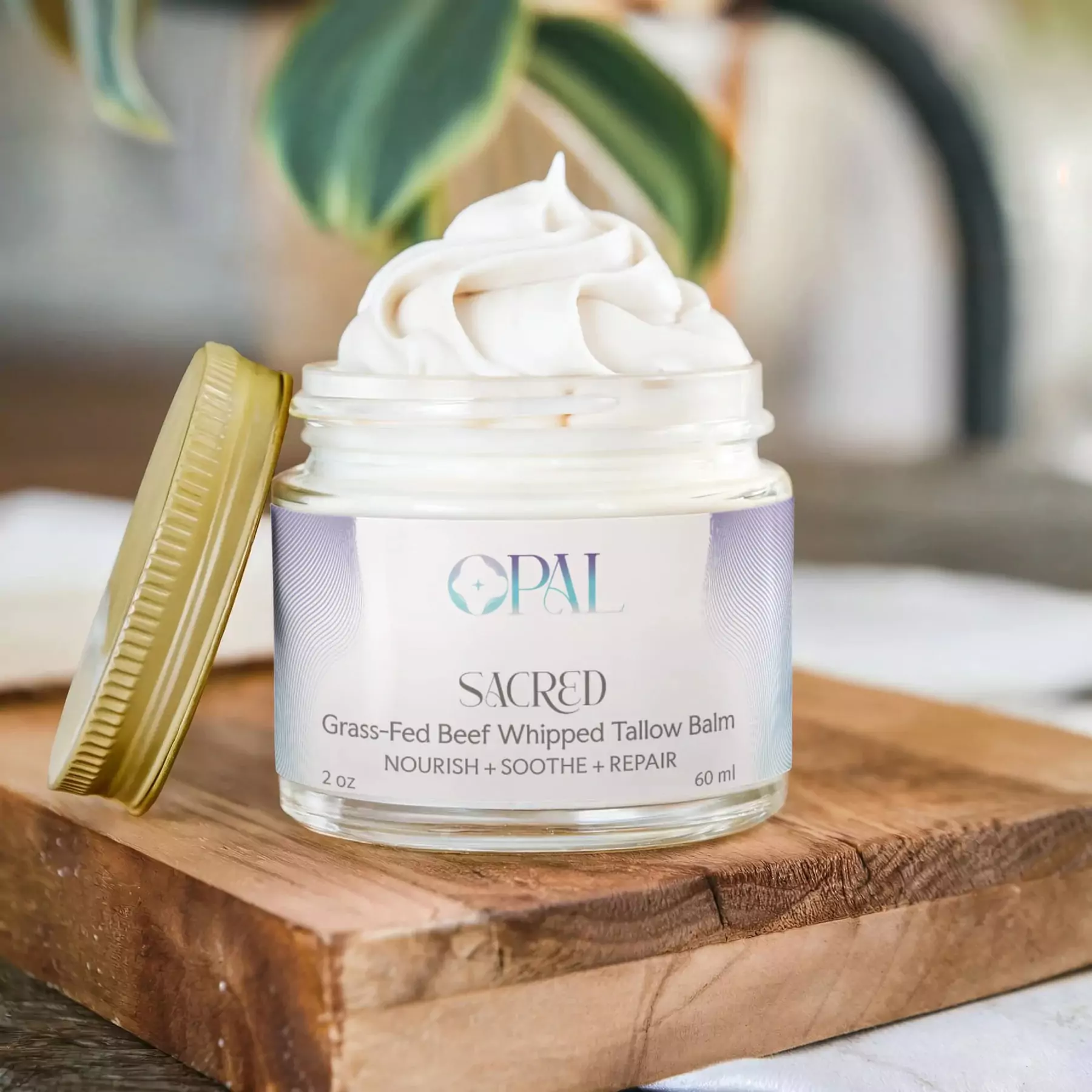 Jar of whipped tallow balm with lid on wooden surface.
