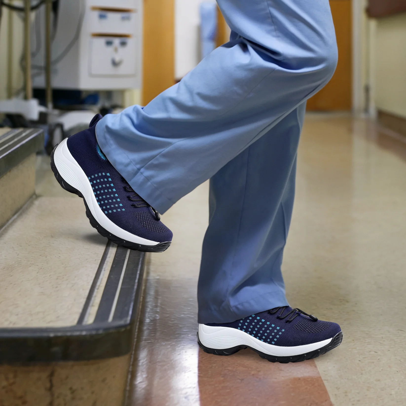 Person in blue pants wearing dark athletic shoes, standing on stairs.