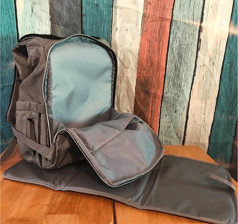 Open gray backpack with a light blue interior on a wooden table.