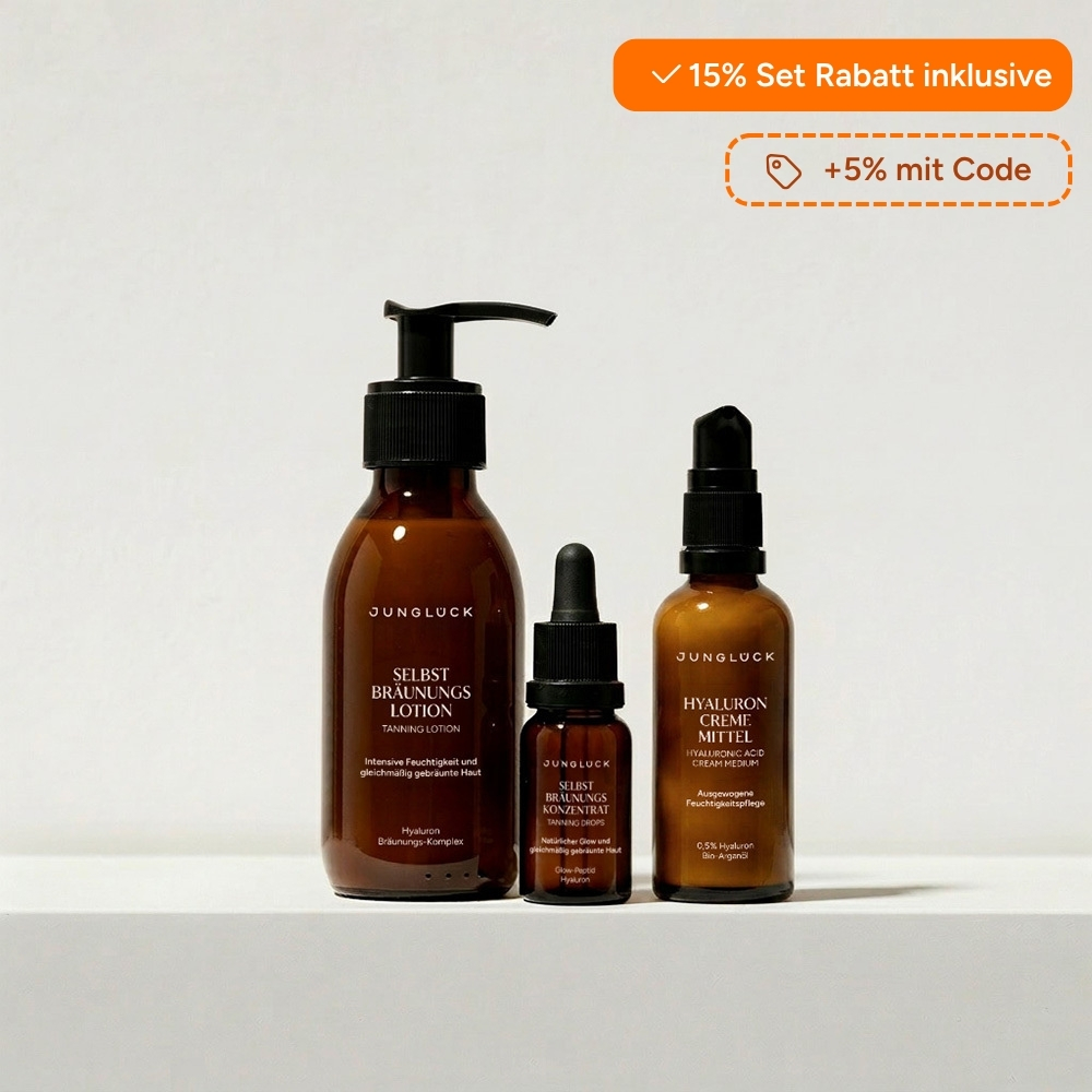 Three brown bottles of Junglück skincare products—a lotion, a concentrate, and a cream—on a white surface.