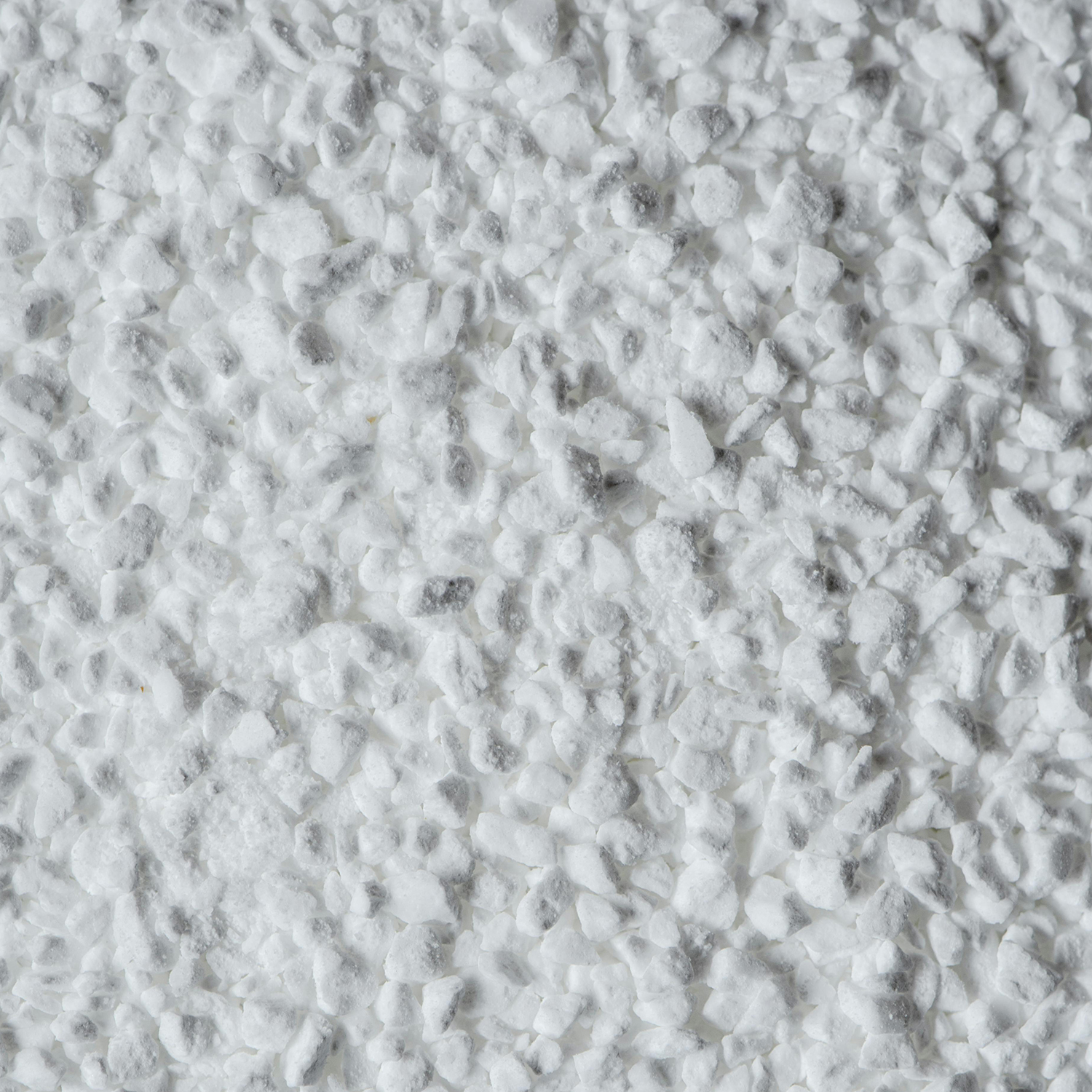 A close-up, grainy, black and white photograph of a white, rocky substance with dark cracks.