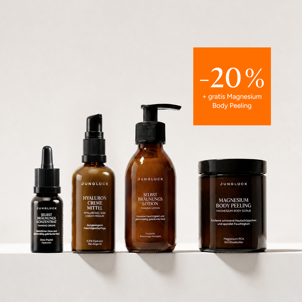 A collection of four Junglück skincare products in amber glass containers with a smear of cream behind them.