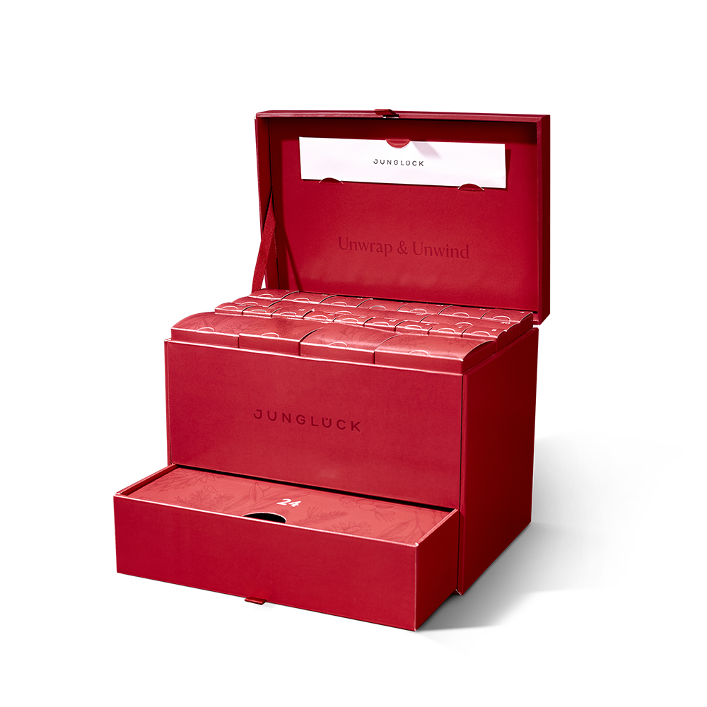 An open red Junglück advent calendar box with multiple compartments and a drawer, against a white background.