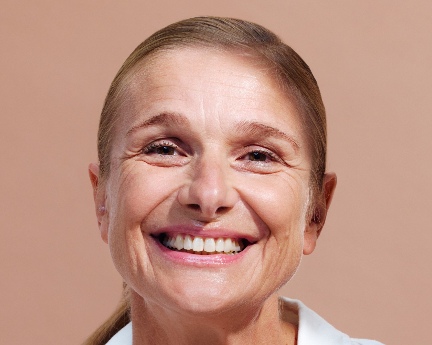 Smiling person with light brown hair against a plain background.