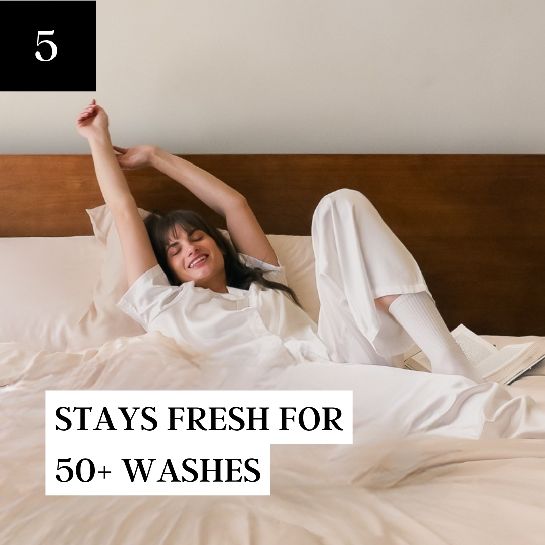 A smiling woman in white pajamas stretches happily in bed with a book next to her.
