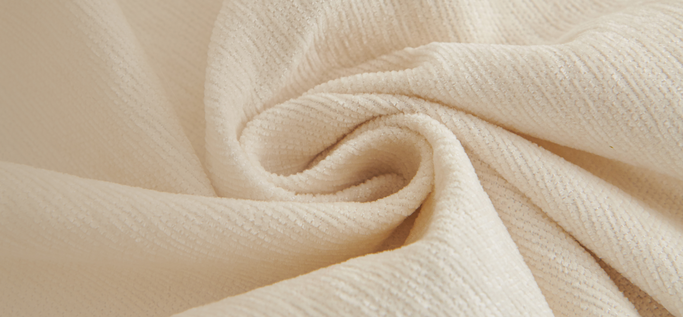 Close-up of beige textured fabric in a swirl pattern.