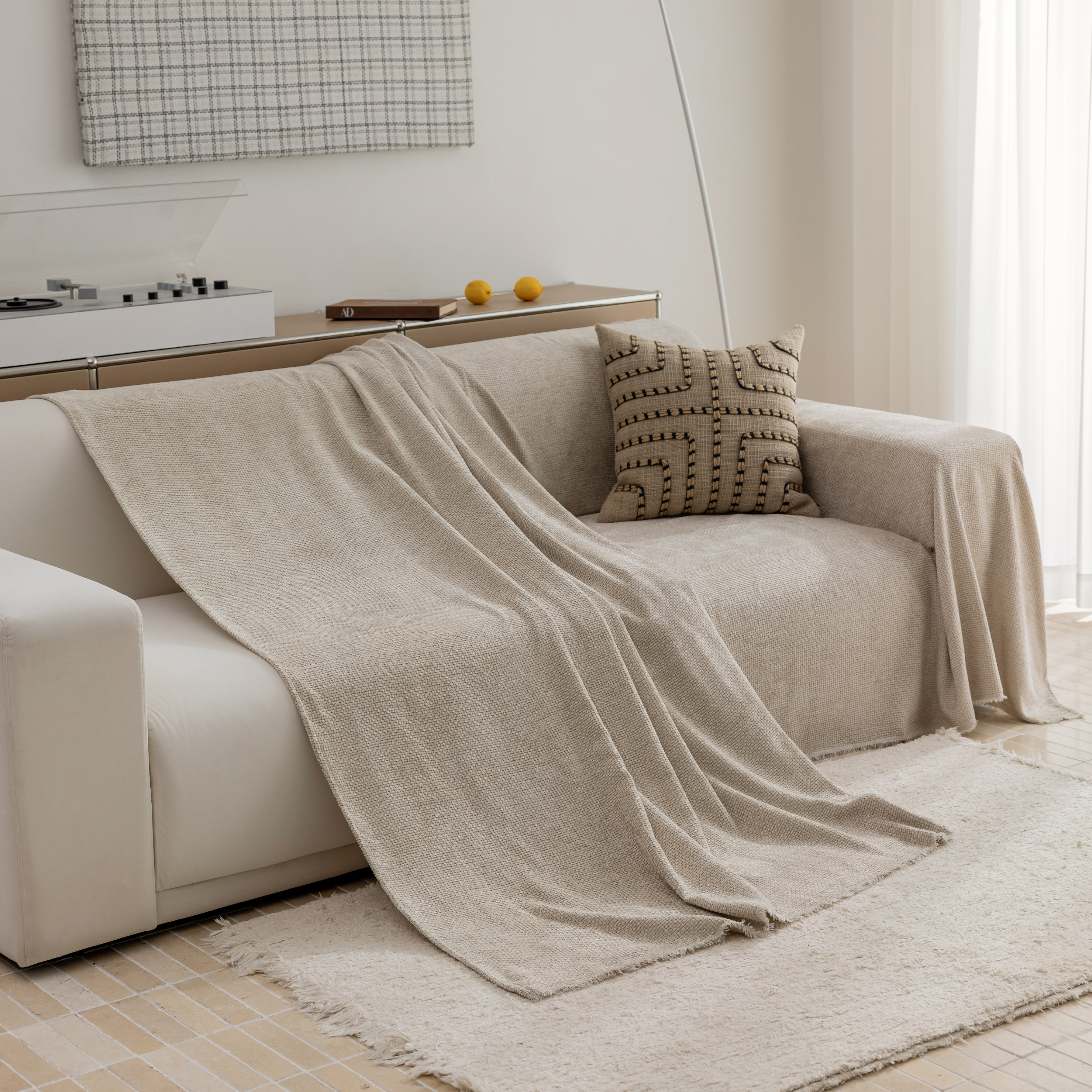 Beige couch with draped blanket, patterned pillow, and two lemons on a nearby console.