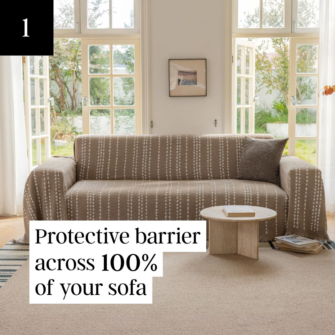 A sofa with a brown and white patterned cover is shown in a sunlit room before large windows.