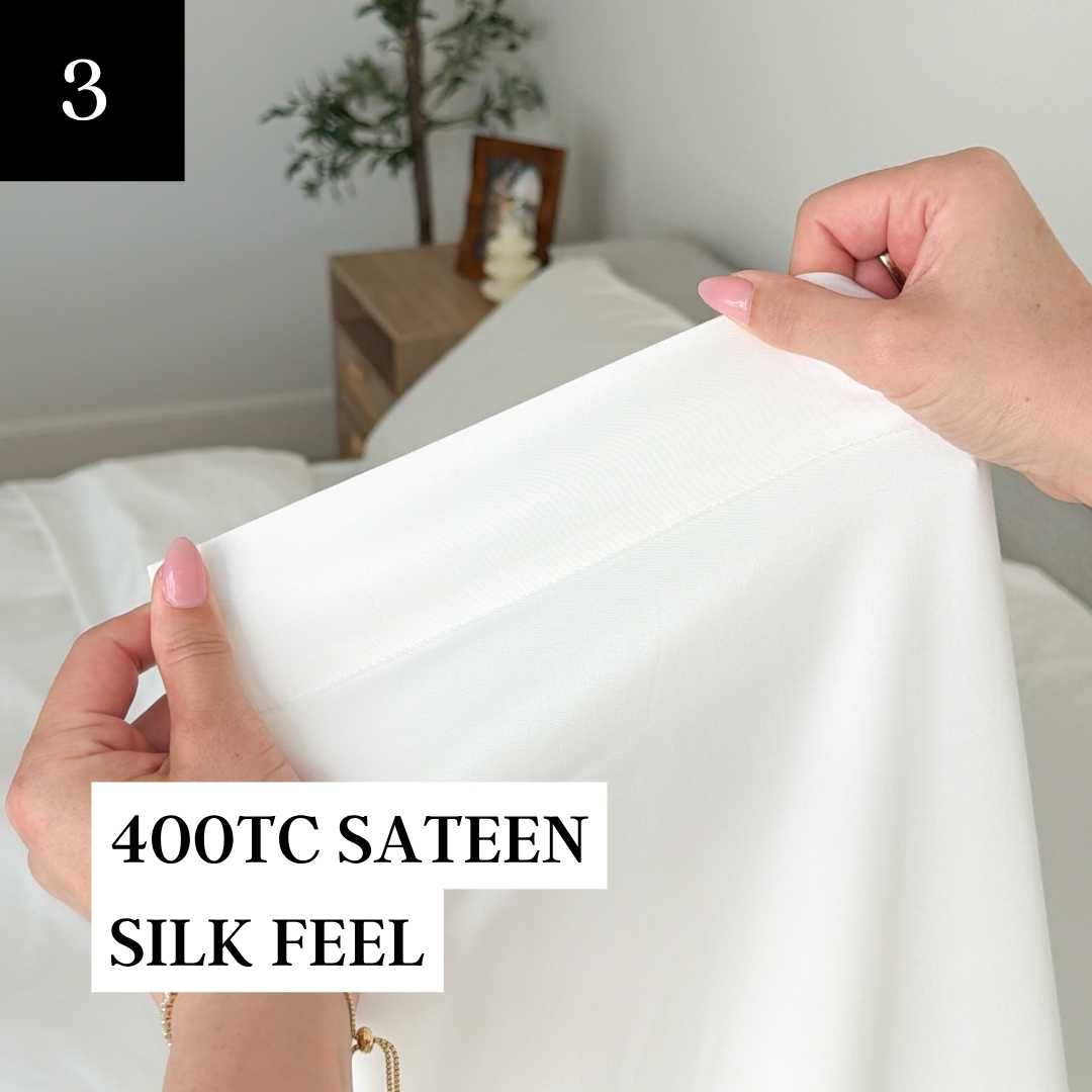 A person's hands with pink nails holding up a white 400TC sateen sheet in a bedroom.