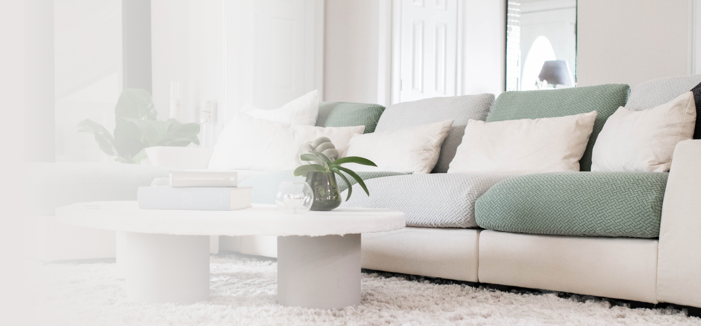 Modern living room with a green sofa, white cushions, and a round coffee table.