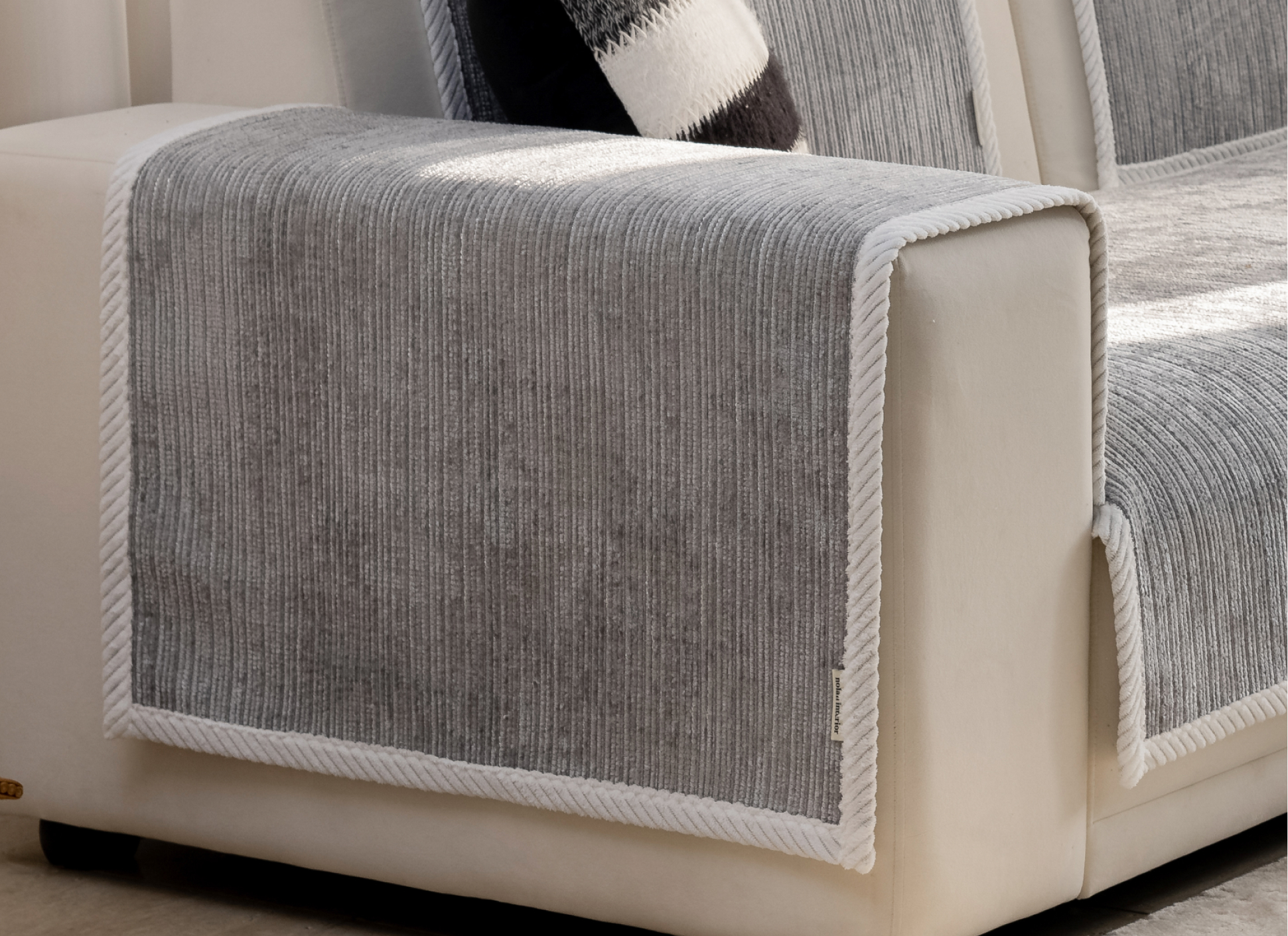 Close-up of gray fabric cover on a beige sofa armrest.