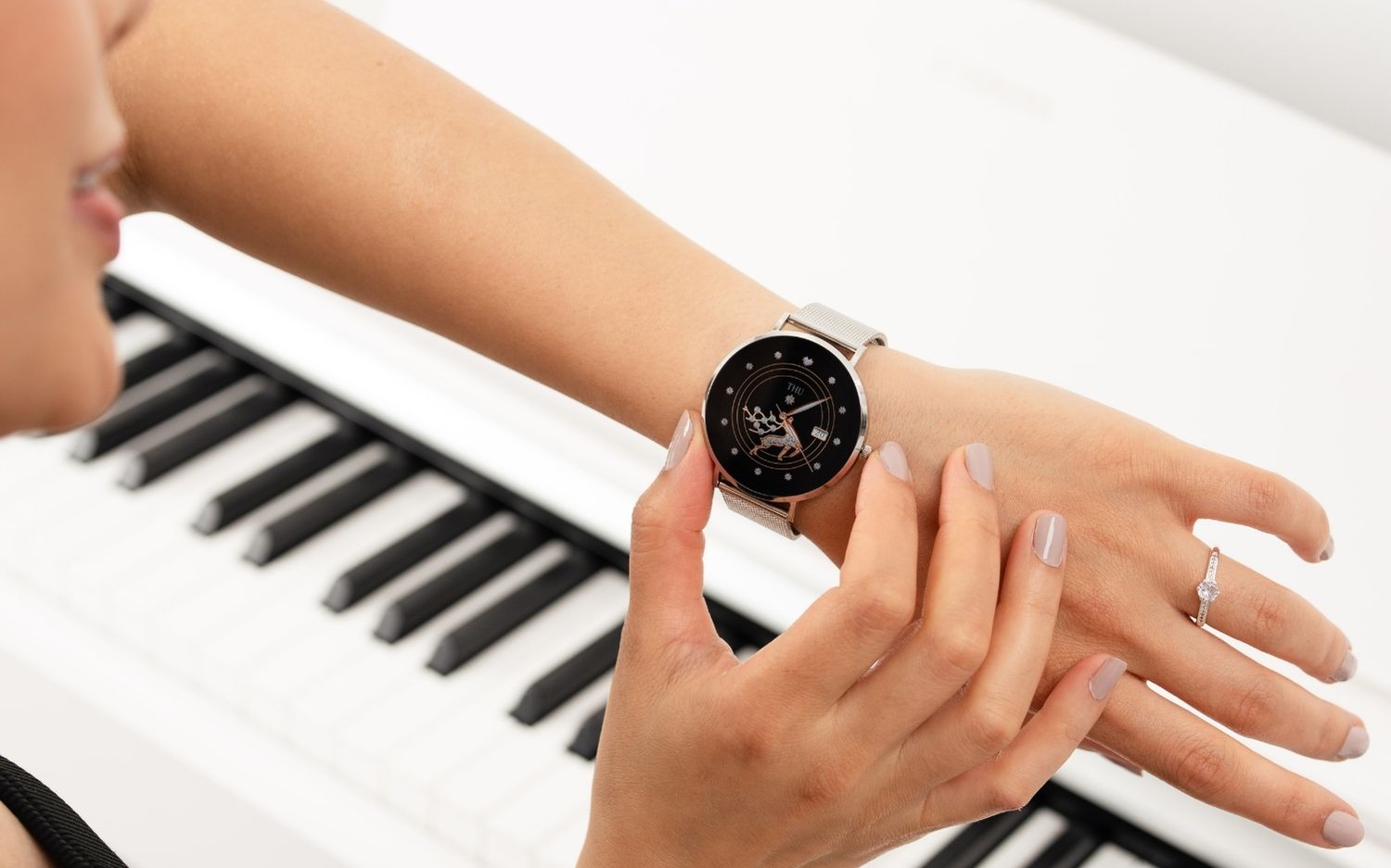 Person adjusting a smartwatch in front of a piano keyboard.