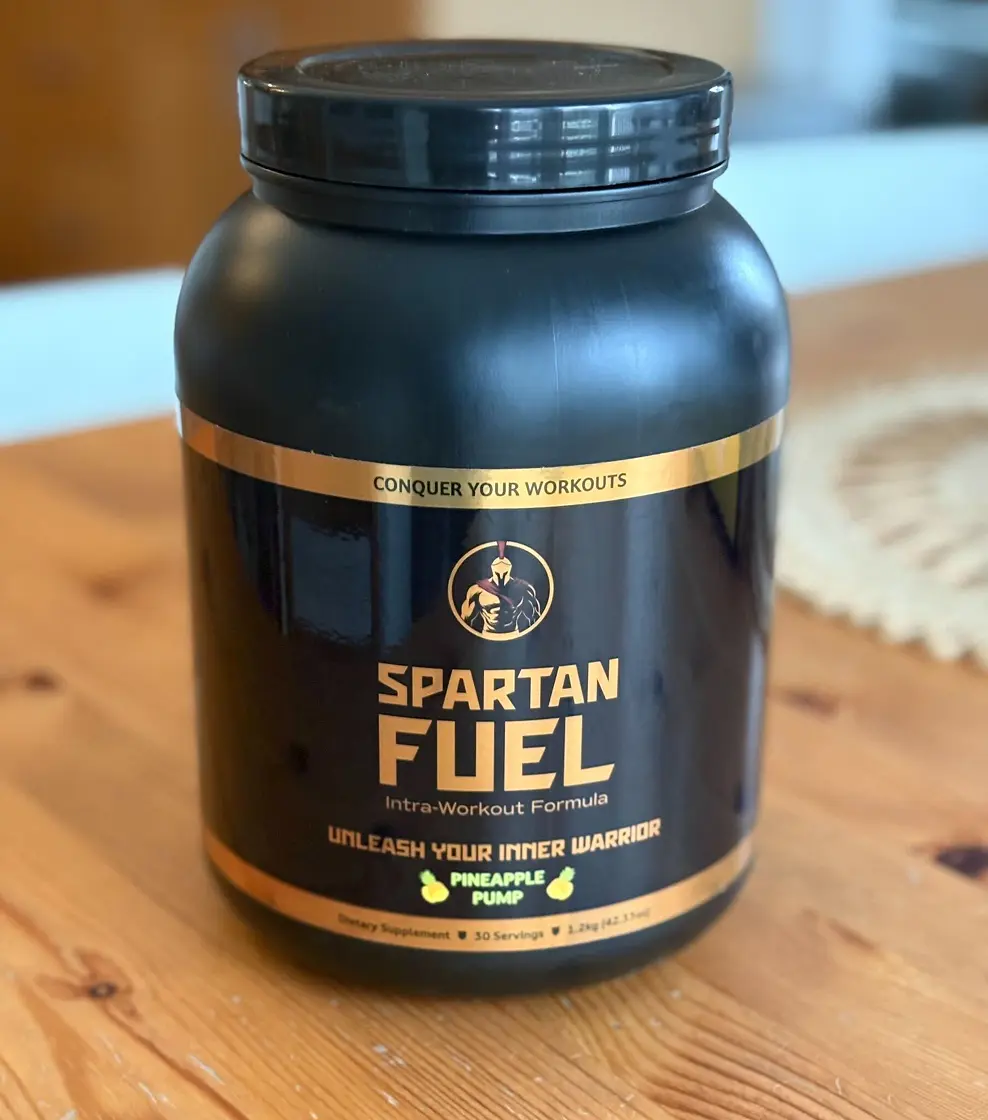 Black container of Spartan Fuel, an intra-workout formula, on a wooden table.