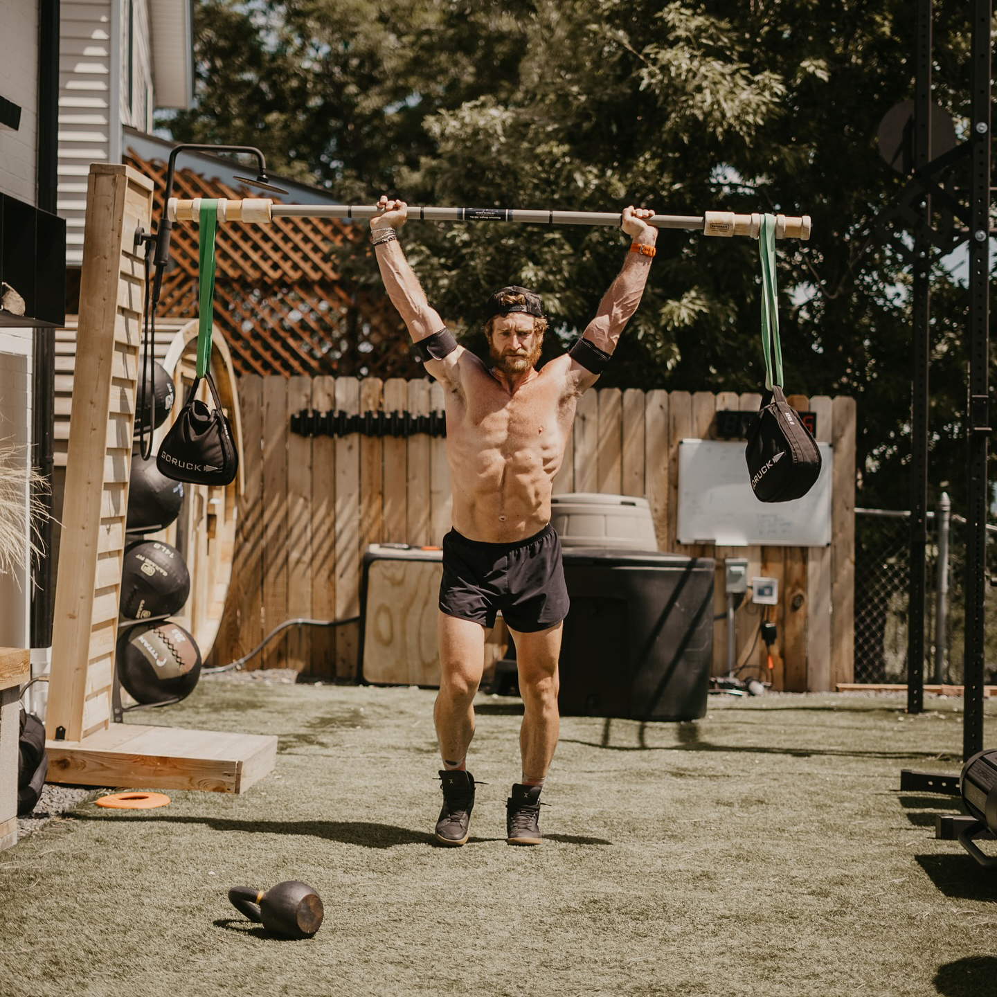 Man lifting a barbell with weights outdoors on artificial grass.