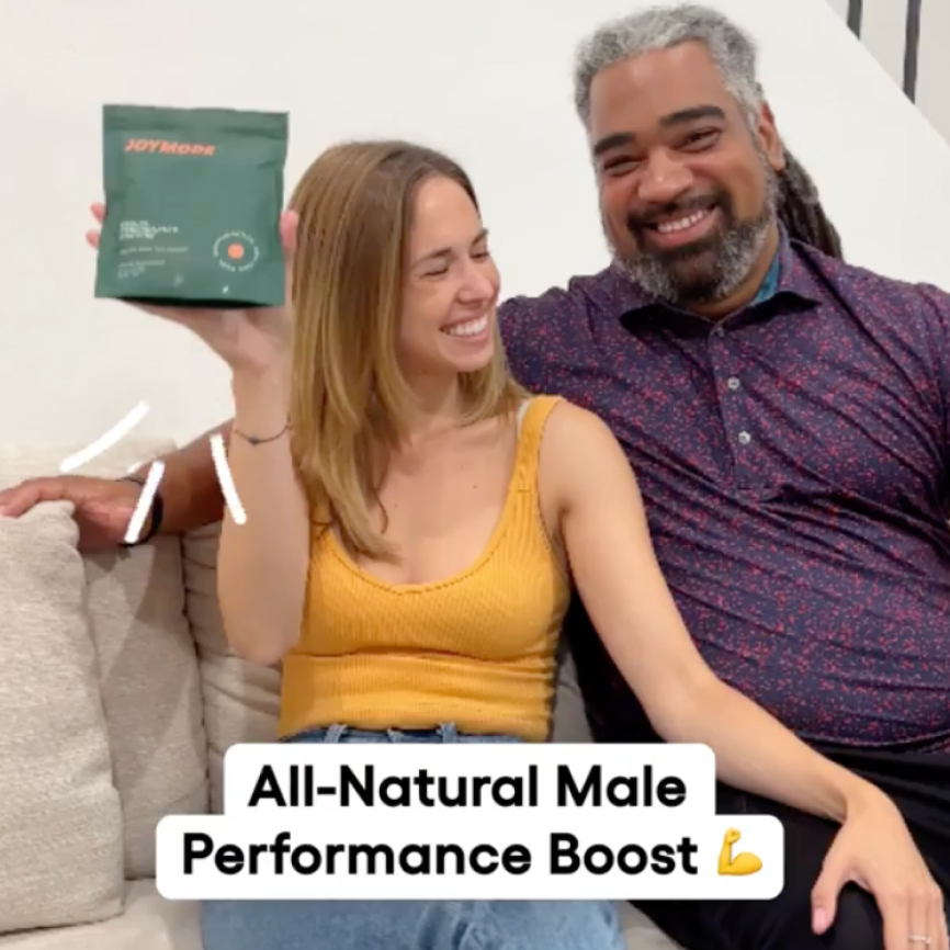 Smiling couple on a couch holding a green product package.