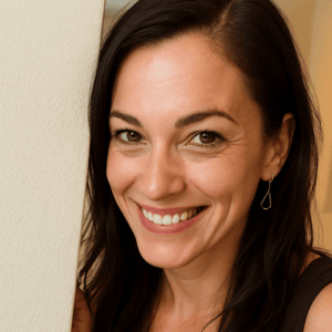 Smiling woman with dark hair and earrings, leaning against a wall.