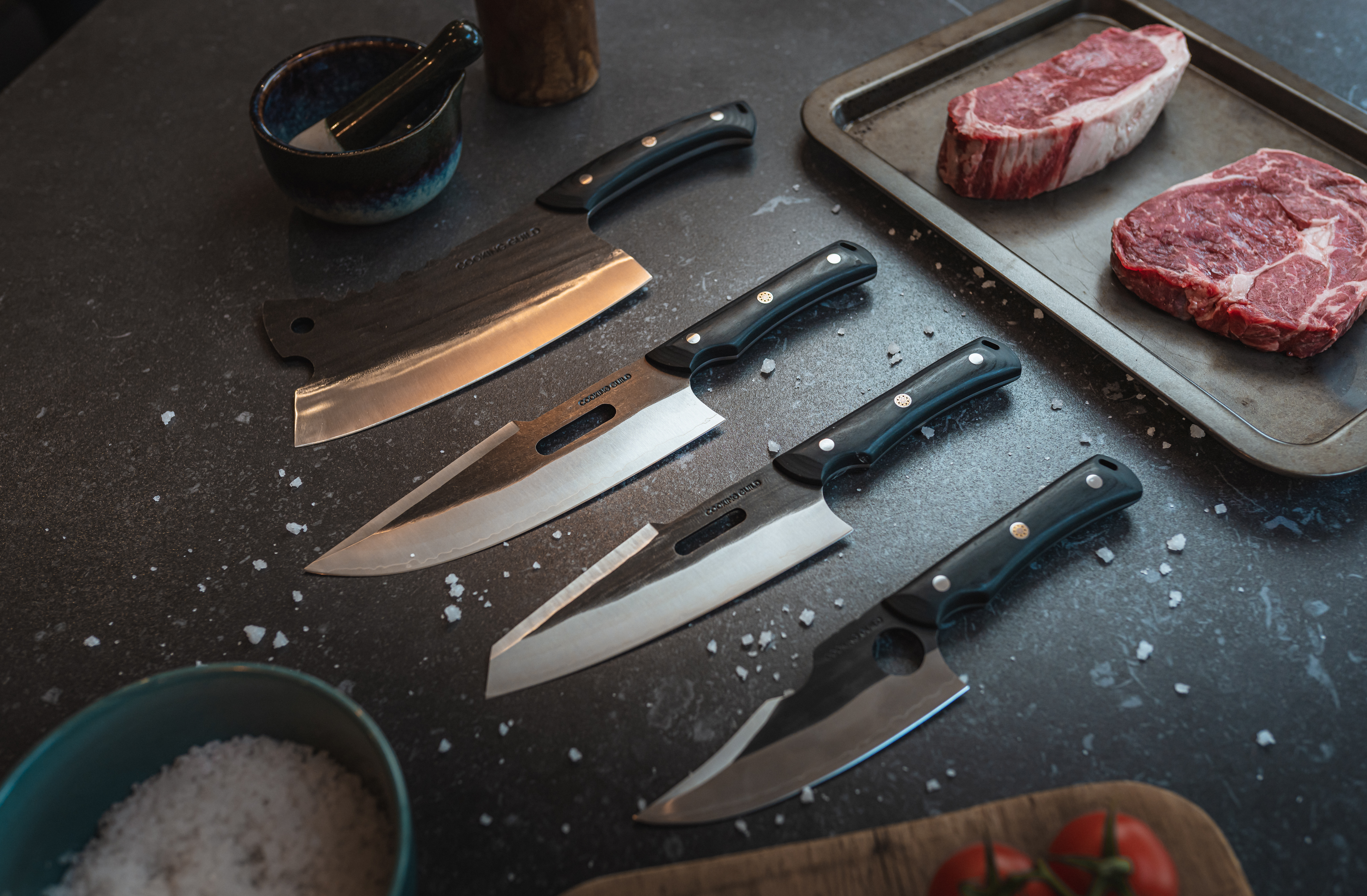 Hands arranging various knives on a wooden surface with vegetables.