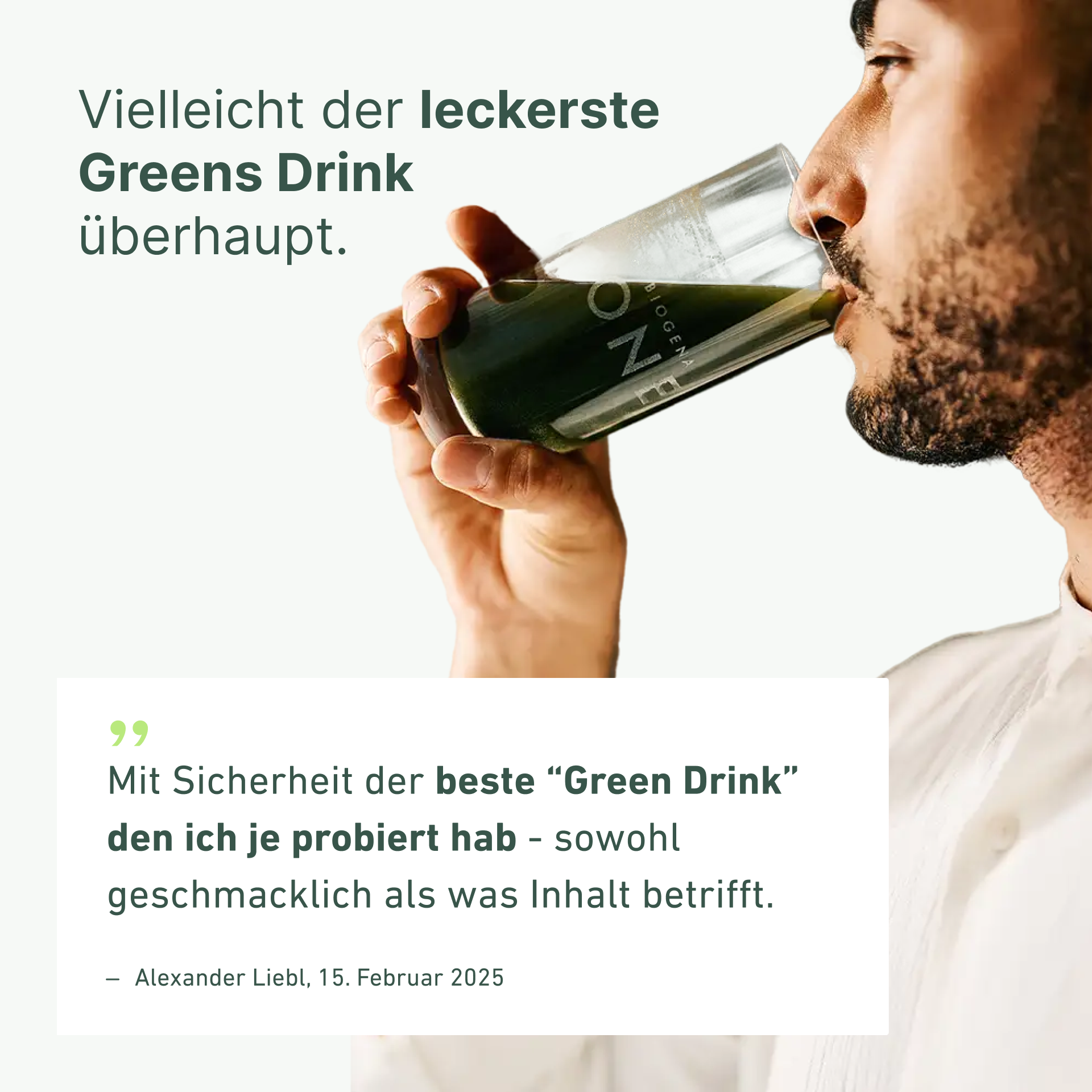 Man drinking a green beverage from a clear bottle outdoors.