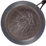 A dark, round pan or skillet with a pile of thin, metallic shavings inside.