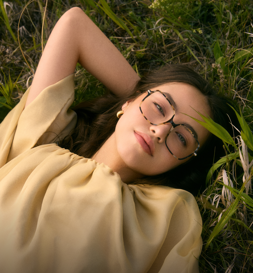 Femme portant des lunettes de soleil en plein air avec des bâtiments en arrière-plan.