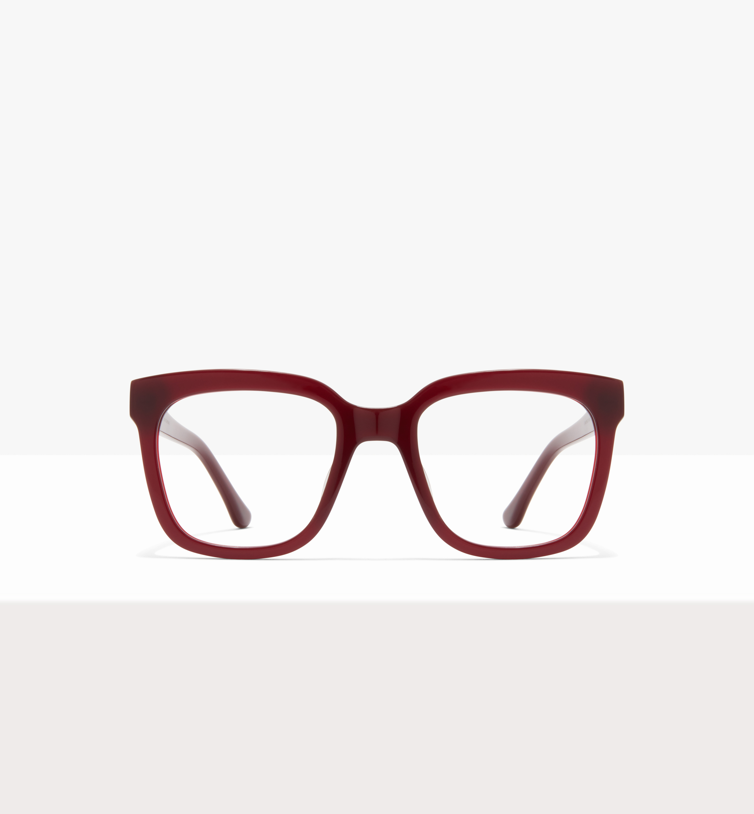 A front view of a pair of dark red, rectangular-framed eyeglasses on a white surface.