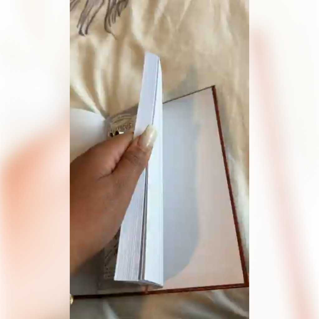 A close-up of a person's hand with long nails flipping through the blank pages of a book.