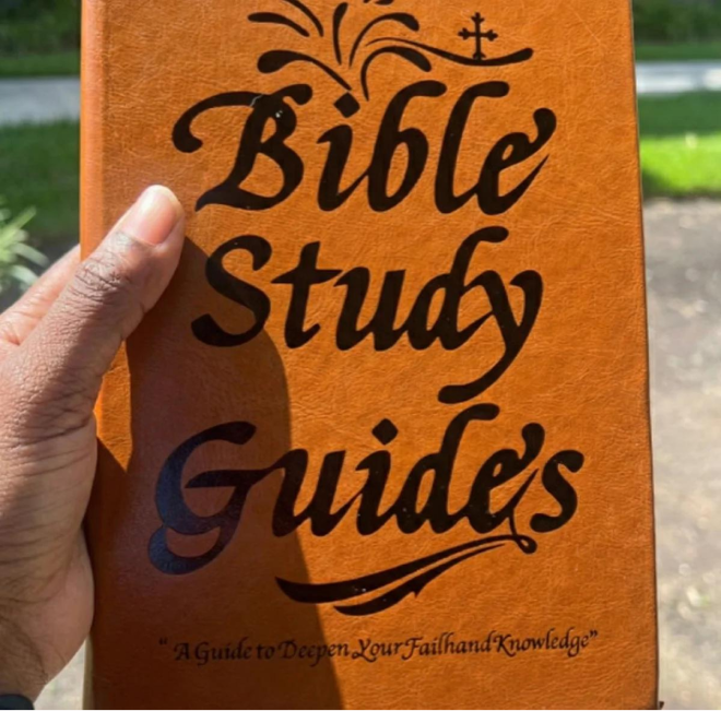 A person's hand holding a brown leather-bound book titled 'Bible Study Guides'.