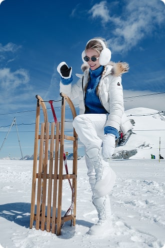 Persoon in winterkleding met een slee op een besneeuwd landschap.