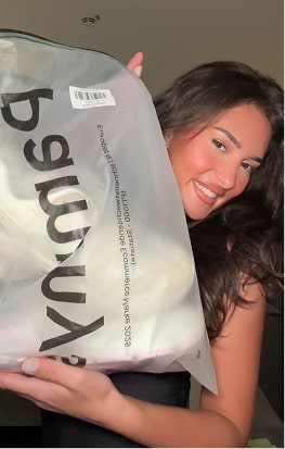 Person smiling and holding a large transparent bag with text on it.