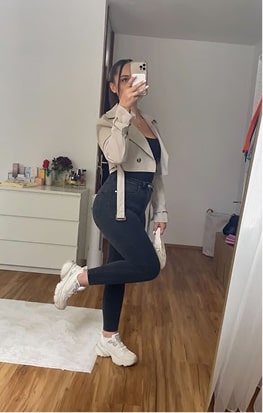 Person taking a mirror selfie in a room with wooden floor and dresser.