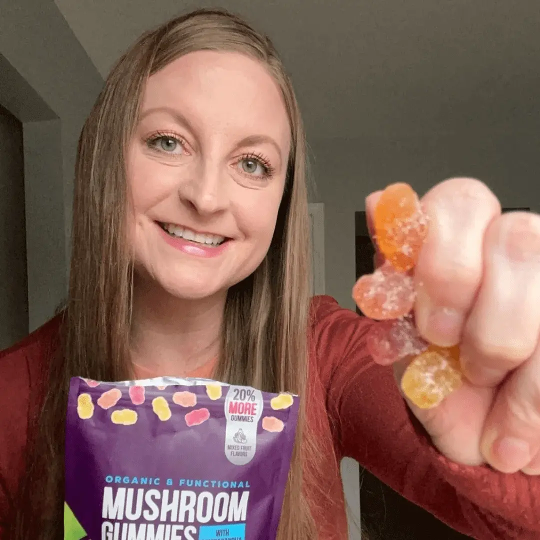 Person holding mushroom gummies and smiling.